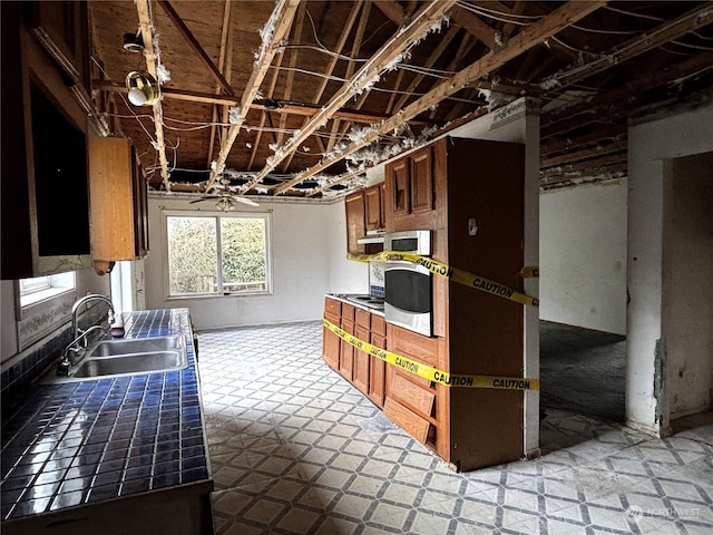 kitchen with sink, tile countertops, oven, and black electric cooktop