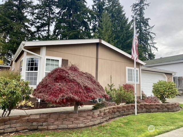 view of side of home featuring a garage and a lawn