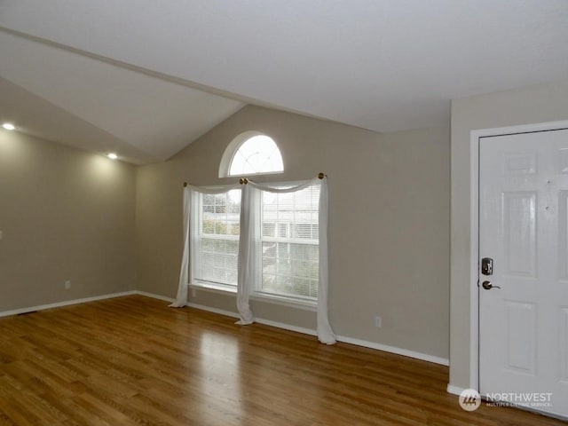 spare room with wood-type flooring and lofted ceiling