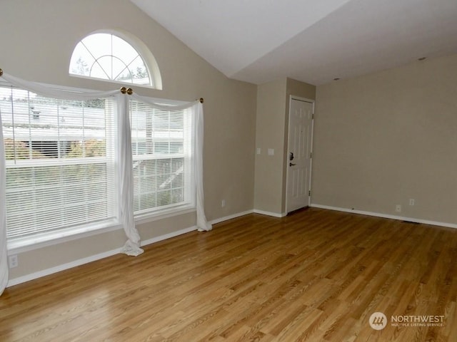 spare room featuring hardwood / wood-style flooring and lofted ceiling