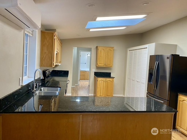 kitchen featuring sink, stainless steel fridge with ice dispenser, dark stone countertops, kitchen peninsula, and a wall unit AC