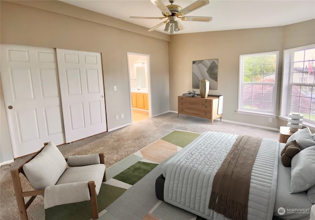 bedroom featuring ensuite bathroom, light colored carpet, and ceiling fan