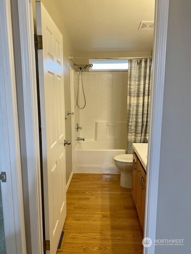 full bathroom with toilet, shower / bath combination with curtain, a textured ceiling, vanity, and hardwood / wood-style flooring