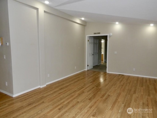 spare room with lofted ceiling and light wood-type flooring