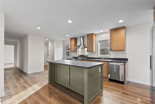 kitchen featuring stainless steel appliances, a center island, wall chimney exhaust hood, and light wood-type flooring