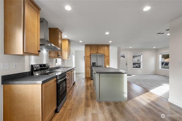 kitchen featuring sink, a center island, light hardwood / wood-style floors, stainless steel appliances, and wall chimney exhaust hood