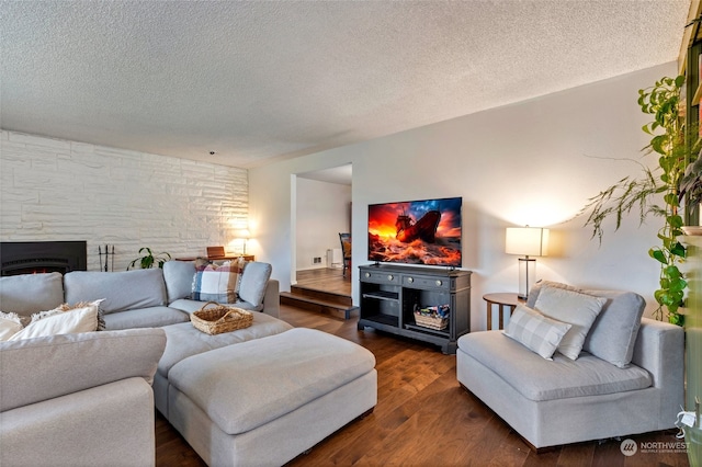 living room featuring a stone fireplace, dark hardwood / wood-style floors, and a textured ceiling