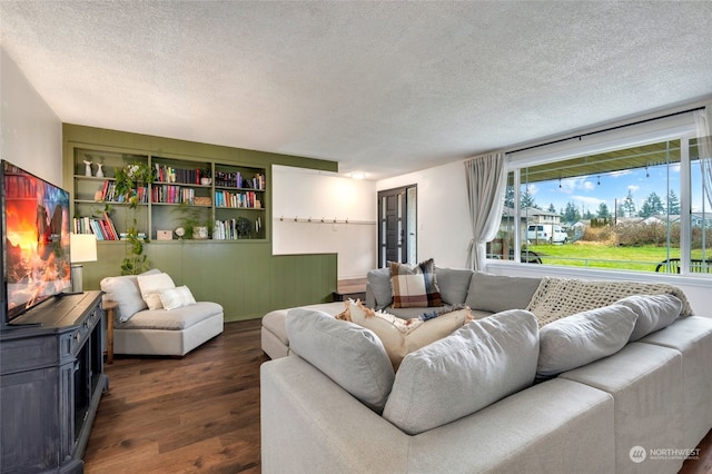 living room featuring dark hardwood / wood-style flooring, built in shelves, and a textured ceiling