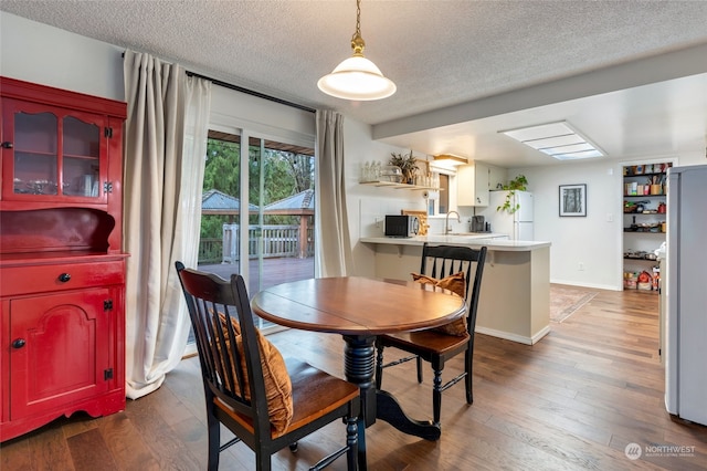 dining space with dark hardwood / wood-style floors, sink, and a textured ceiling