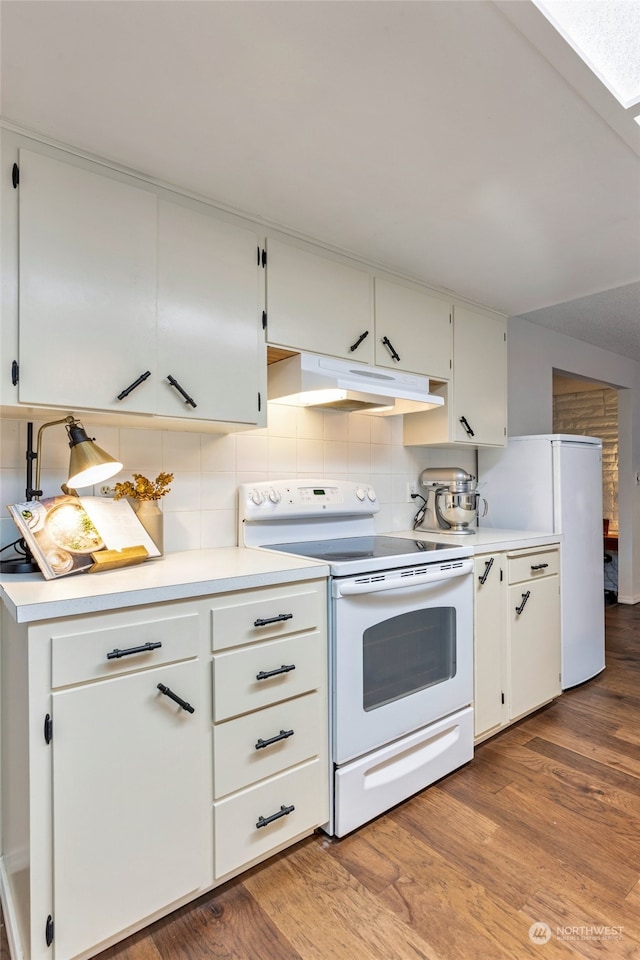 kitchen with white appliances, wood-type flooring, decorative backsplash, and white cabinets