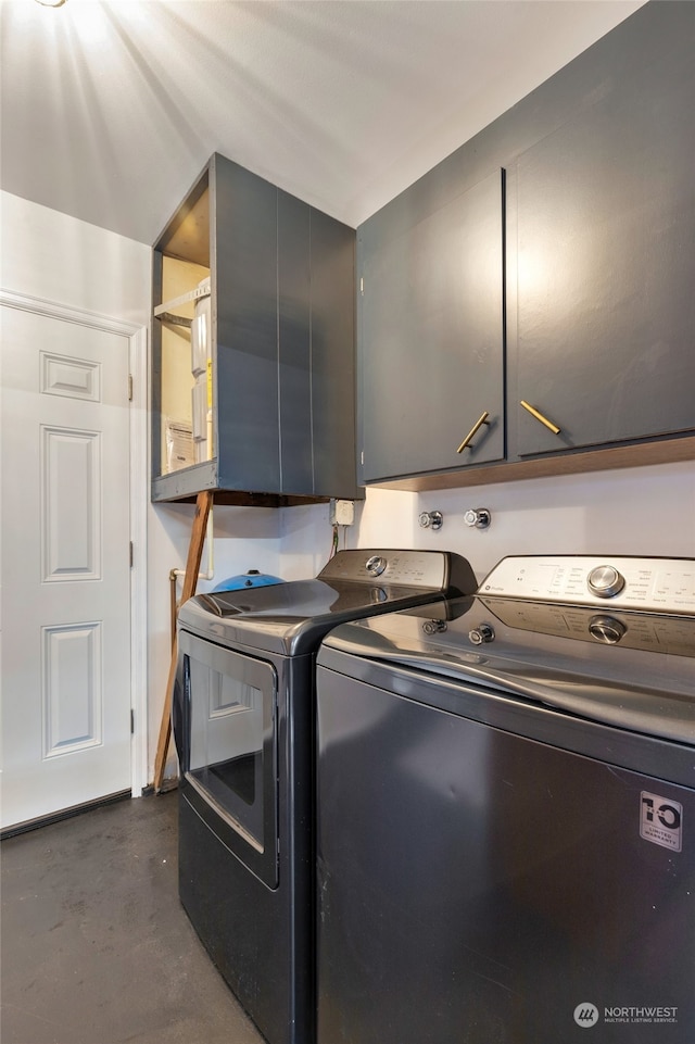 clothes washing area with cabinets and washer and clothes dryer