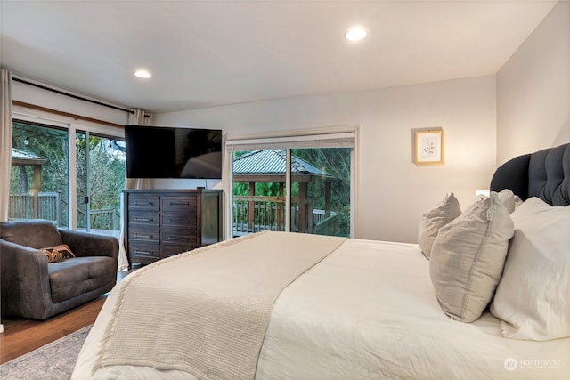 bedroom with multiple windows, access to outside, and hardwood / wood-style floors