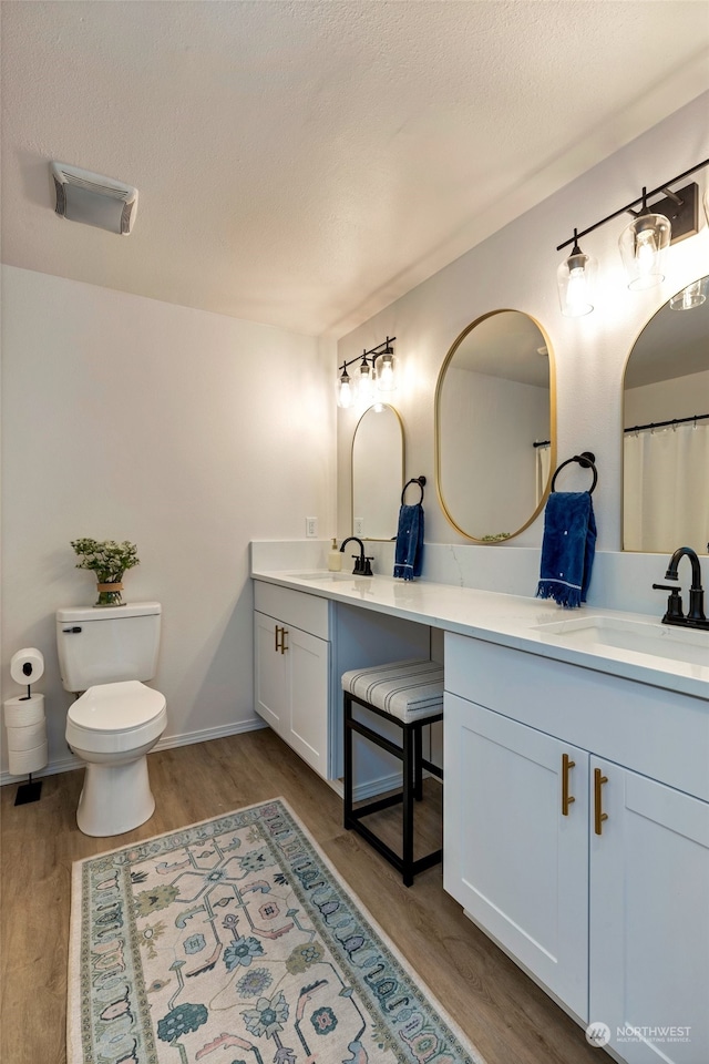 bathroom featuring hardwood / wood-style flooring, vanity, a textured ceiling, and toilet