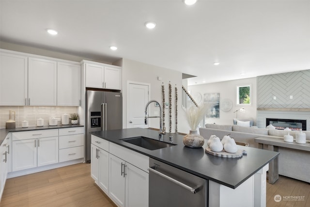 kitchen with dark countertops, appliances with stainless steel finishes, open floor plan, white cabinetry, and a sink