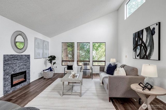 living room with high vaulted ceiling, a fireplace, a textured ceiling, and wood finished floors