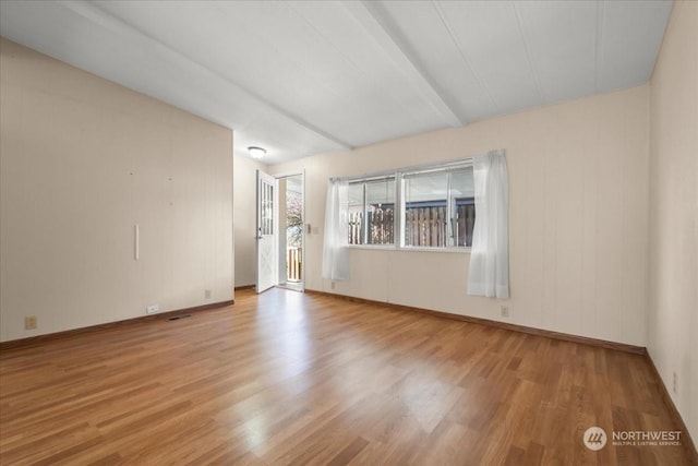 unfurnished room with beamed ceiling and light hardwood / wood-style floors