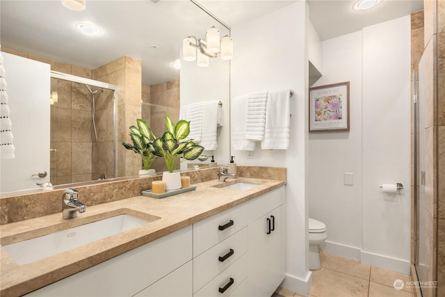 bathroom featuring tile patterned flooring, vanity, a shower with shower door, and toilet