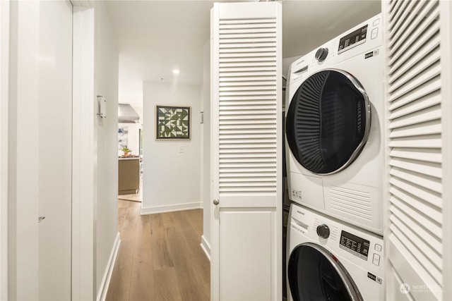 laundry room featuring stacked washer and dryer and light wood-type flooring