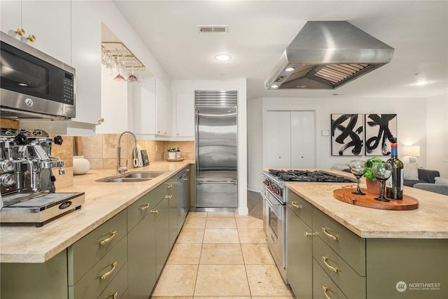 kitchen with island range hood, high quality appliances, sink, and white cabinets