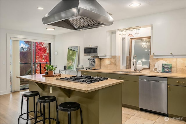 kitchen with white cabinets, a kitchen bar, island exhaust hood, a center island, and stainless steel appliances