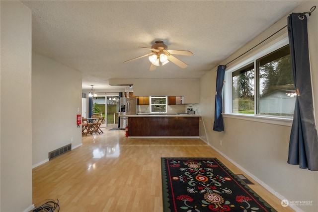 kitchen featuring stainless steel fridge, kitchen peninsula, light hardwood / wood-style flooring, and a textured ceiling