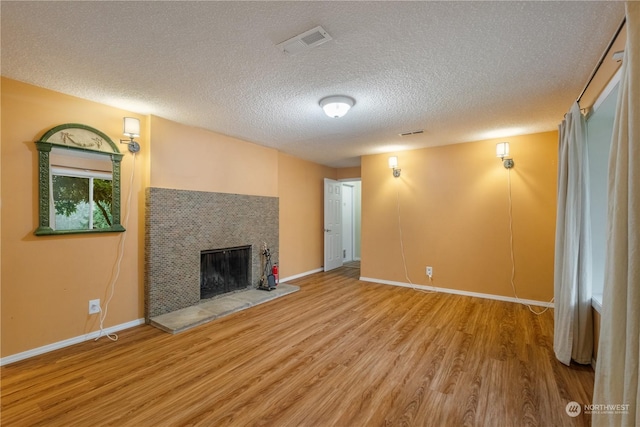 unfurnished living room with hardwood / wood-style flooring, a fireplace, and a textured ceiling