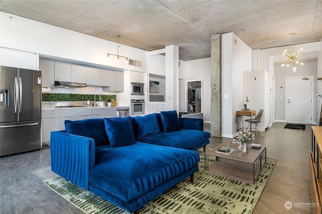 living room with a towering ceiling, a chandelier, and sink