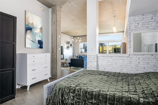 bedroom with concrete flooring, brick wall, and a chandelier