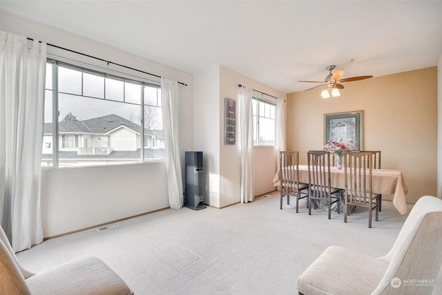 carpeted dining area featuring baseboards, visible vents, and ceiling fan