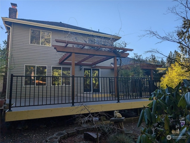 rear view of house with a wooden deck and a pergola