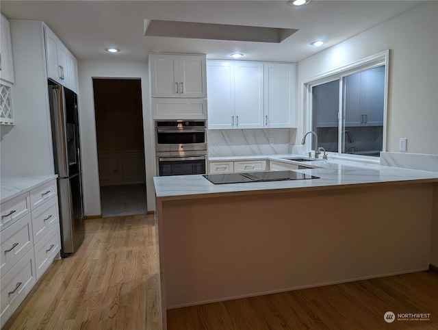 kitchen with white cabinetry, sink, stainless steel appliances, and kitchen peninsula