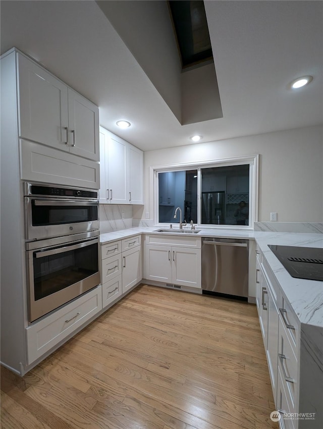 kitchen featuring white cabinetry, stainless steel appliances, sink, and light hardwood / wood-style flooring