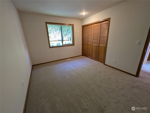 unfurnished bedroom with light carpet and a closet