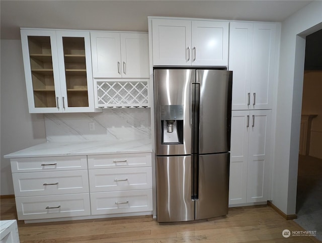 kitchen with light stone countertops, white cabinets, backsplash, and stainless steel fridge with ice dispenser