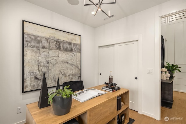 home office featuring light hardwood / wood-style floors and a chandelier