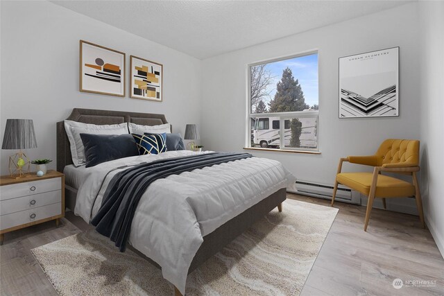 bedroom with baseboard heating, light hardwood / wood-style flooring, and a textured ceiling