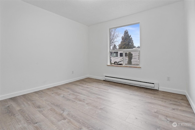 unfurnished room with a baseboard radiator, a textured ceiling, and light hardwood / wood-style flooring