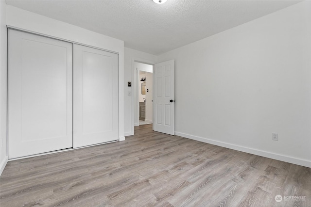 unfurnished bedroom featuring light hardwood / wood-style floors, a closet, and a textured ceiling