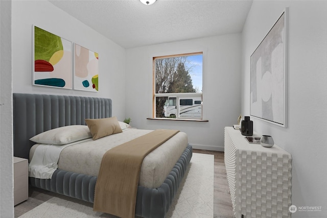 bedroom with radiator, a textured ceiling, and light hardwood / wood-style floors