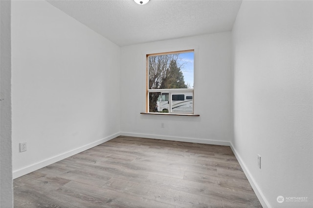 unfurnished room featuring a textured ceiling and light wood-type flooring