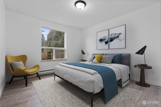 bedroom with wood-type flooring, a textured ceiling, and baseboard heating