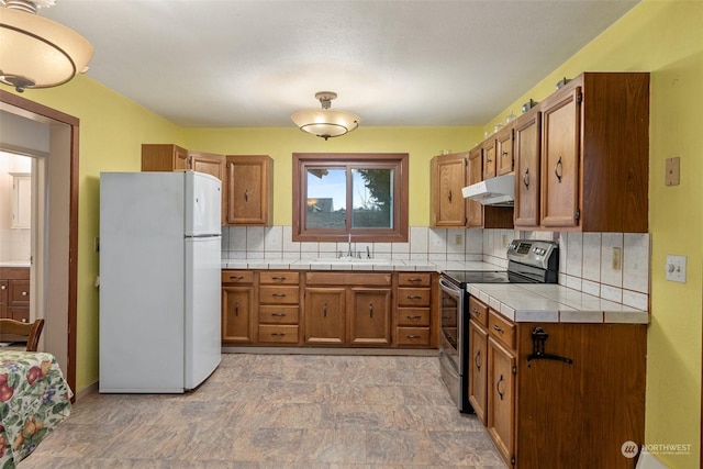 kitchen featuring white refrigerator, tile counters, electric stove, and tasteful backsplash