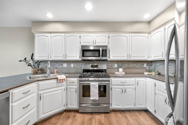 kitchen featuring stainless steel appliances, light hardwood / wood-style floors, sink, and white cabinets