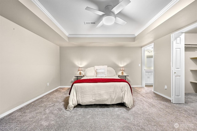 carpeted bedroom with ornamental molding, a walk in closet, ceiling fan, and a tray ceiling