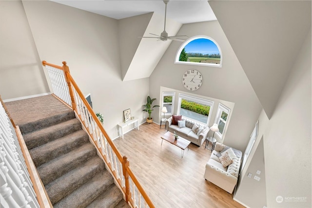 living room featuring a towering ceiling, wood-type flooring, and a healthy amount of sunlight