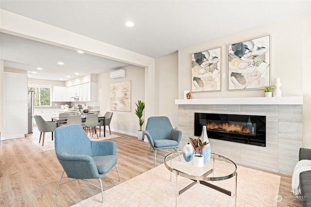 living room with a fireplace, a wall unit AC, and light hardwood / wood-style flooring