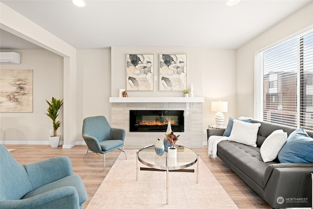 living room with a tiled fireplace, a wall mounted AC, and hardwood / wood-style floors