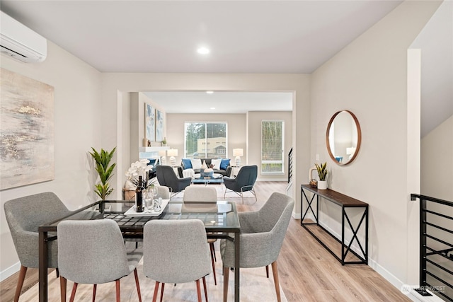 dining space featuring a wall mounted air conditioner and light hardwood / wood-style flooring