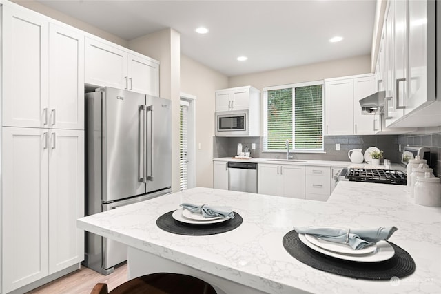 kitchen featuring white cabinetry, appliances with stainless steel finishes, kitchen peninsula, and sink