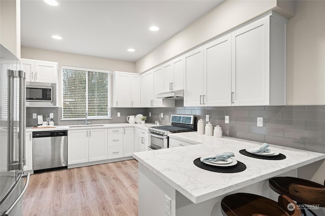 kitchen featuring white cabinetry, sink, light stone counters, kitchen peninsula, and stainless steel appliances